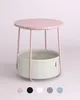 A product shot of a pink side table with a fabric basket underneath, set against a light pink background. Náhled obrázku produktu