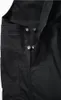 A close-up view of the black fabric and metal snap buttons of a pair of overalls. Produktbild-Vorschau