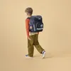 A young boy walks away from the camera, wearing a backpack. Náhled obrázku produktu