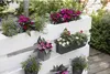 A white wooden pallet planter filled with various colorful flowers and greenery, set outdoors on a wooden deck. Voir les images du produit