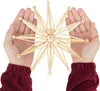 Hands holding a straw star ornament against a white background. Produktbild-Vorschau