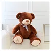 A large brown teddy bear sits on a white armchair. Podgląd zdjęcia produktu