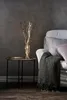 A decorative branch with LED lights in a vase on a side table next to a sofa. Podgląd zdjęcia produktu