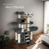 A cat tree with two cats, one orange and one tabby, is shown in a room with a bed and a plant. Náhled obrázku produktu