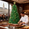 A chocolatier is making chocolates in front of a Christmas tree in a shop window, with people looking in from outside. Voir les images du produit