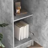 A close-up view of a gray concrete-effect cabinet with shelves holding books and decorative items. Podgląd zdjęcia produktu