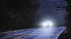 A car driving on a wet road at night with its headlights on. Produktbild-Vorschau