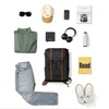 A flat lay of clothing and accessories, including a backpack, jeans, a sweater, a hat, sunglasses, headphones, a phone, a wallet, a water bottle, and books. Produktbild-Vorschau