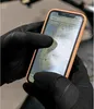 A person wearing black gloves is using a smartphone with a map application open. Produktbild-Vorschau