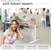 A woman is holding her hand to her ear, listening, in front of a standing desk with a sound-absorbing partition. Arrows indicate sound waves being directed away from the desk area. Náhled obrázku produktu