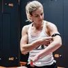A woman in a gym setting adjusts a black arm band on her bicep. Náhled obrázku produktu