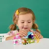 A young girl is playing with a LEGO Friends Welpenspielplatz set on a white table. Náhľad obrázku produktu