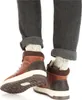 A close-up view of a person's feet wearing brown boots and gray pants. Anteprima dell’immagine prodotto