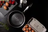 A frying pan with eggs and tomatoes on a black surface. Náhľad obrázku produktu