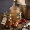 A still life arrangement of pickled onions and other ingredients in jars and on a wooden surface, with a large metal pot in the background. Anteprima dell’immagine prodotto