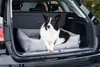 A dog is lying in a dog bed in the trunk of a car. Produktbild-Vorschau