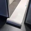 A roll of white protective paper is unrolling onto a tiled floor, extending through a doorway. Produktbild-Vorschau