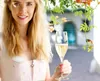 A woman in traditional clothing holds a glass of champagne. Produktbild-Vorschau