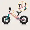 A pink balance bike with teal accents, shown with arrows indicating adjustability and a close-up inset of a hand holding a part of the frame. Produktbild-Vorschau