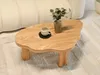 A wooden coffee table with a vase and a cup on it, placed on a rug next to a sofa. Anteprima dell’immagine prodotto