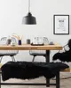 A dining room setting with a wooden table, chairs, and a bench covered with a black sheepskin rug. Produktbild-Vorschau