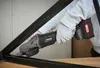 A person wearing gloves is using a cordless angle grinder on a metal frame. Produktbild-Vorschau