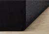 A close-up view of the corner of a black rug, showing its textured surface and the patterned anti-slip backing. Produktbild-Vorschau