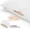 A close-up view of a white pillow with a cut-out showing its filling, and a pile of the filling material next to it. Produktbild-Vorschau