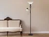A floor lamp with a reading light next to a sofa against a plain wall. Produktbild-Vorschau
