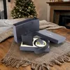 A gift set for men, including a wallet and belt, is displayed on a rug in front of a Christmas tree and fireplace. Anteprima dell’immagine prodotto