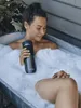 A woman is taking a bath with a travel mug in her hand. Anteprima dell’immagine prodotto
