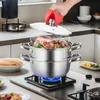 A hand using a red silicone mitt to lift the lid of a steaming stainless steel pot on a stovetop, revealing a lobster and vegetables inside. Produktbild-Vorschau