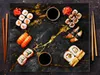 A top-down view of a marble serving board with various sushi dishes, soy sauce, and chopsticks. Náhľad obrázku produktu