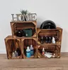 Wooden crates are stacked and used as shelving to display various items, including nail polish, bottles, a handbag, and decorative elements. Produktbild-Vorschau