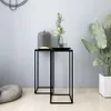 Two black metal side tables with decorative items on top, placed in a room with a plant and a beanbag. Anteprima dell’immagine prodotto