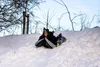 A person is sledding down a snowy hill on a tube. Produktbild-Vorschau