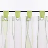 A close-up view of green and white striped sheer curtains hanging from a black rod. Produktbild-Vorschau