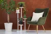 A plant stand with multiple potted plants next to a green armchair with a white pillow. Anteprima dell’immagine prodotto