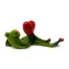 A ceramic figurine of a green frog lying down and holding a red heart. Produktbild-Vorschau