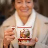A woman is holding a festive mug with a Christmas design. Voir les images du produit