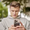 A young man is looking at his phone, which has a magnetic wireless power bank attached. Produktbild-Vorschau
