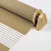 A close-up view of a beige and white roller blind, showing the fabric texture and the roller mechanism. Produktbild-Vorschau