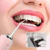 A close-up of a person's mouth with braces, using a pink water flosser to clean their teeth. A smaller inset image shows someone flossing their teeth with braces. Náhľad obrázku produktu