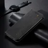 A black leather flip case for a smartphone is displayed on a dark surface, with a smartwatch in the background. Produktbild-Vorschau