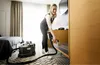 A woman is cleaning a hotel room with a Kärcher Puzzi 9/1 BP Waschsauger. Produktbild-Vorschau