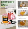 A collection of glass jars with lids, some filled with food, along with labels and cutlery, presented on a table. Produktbild-Vorschau