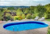 An oval swimming pool in a backyard setting with lounge chairs and landscaping. Náhľad obrázku produktu
