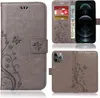 A collage of images showing a gray flip phone case with a floral and butterfly design for an Apple iPhone 13 Pro Max, including views of the case open with cards and cash, and the back of the case with the camera cutout. Produktbild-Vorschau