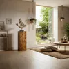 A living room with a large window overlooking a garden, featuring a wooden decorative column with a sculpture on top. Anteprima dell’immagine prodotto