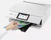 A hand is inserting a document into a white Canon PIXMA TS8751 WLAN color multifunction photo printer. Podgląd zdjęcia produktu